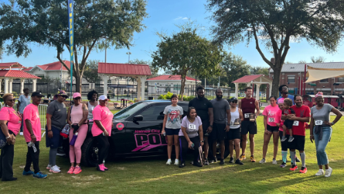 participants from a 5k race lined up standing in front of a police car in a park